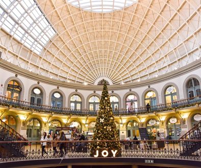 Leeds Corn Exchange christmas tree with warm lighting and an LED Letter sign that reads 'JOY',