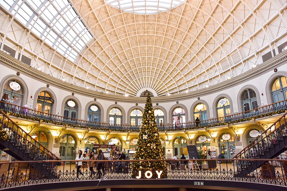 Leeds Corn Exchange christmas tree with warm lighting and an LED Letter sign that reads 'JOY',