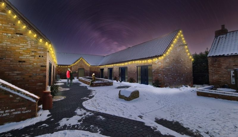 a barn conversion with Warm White LED Festoon lights draped around the gutters of the barn.